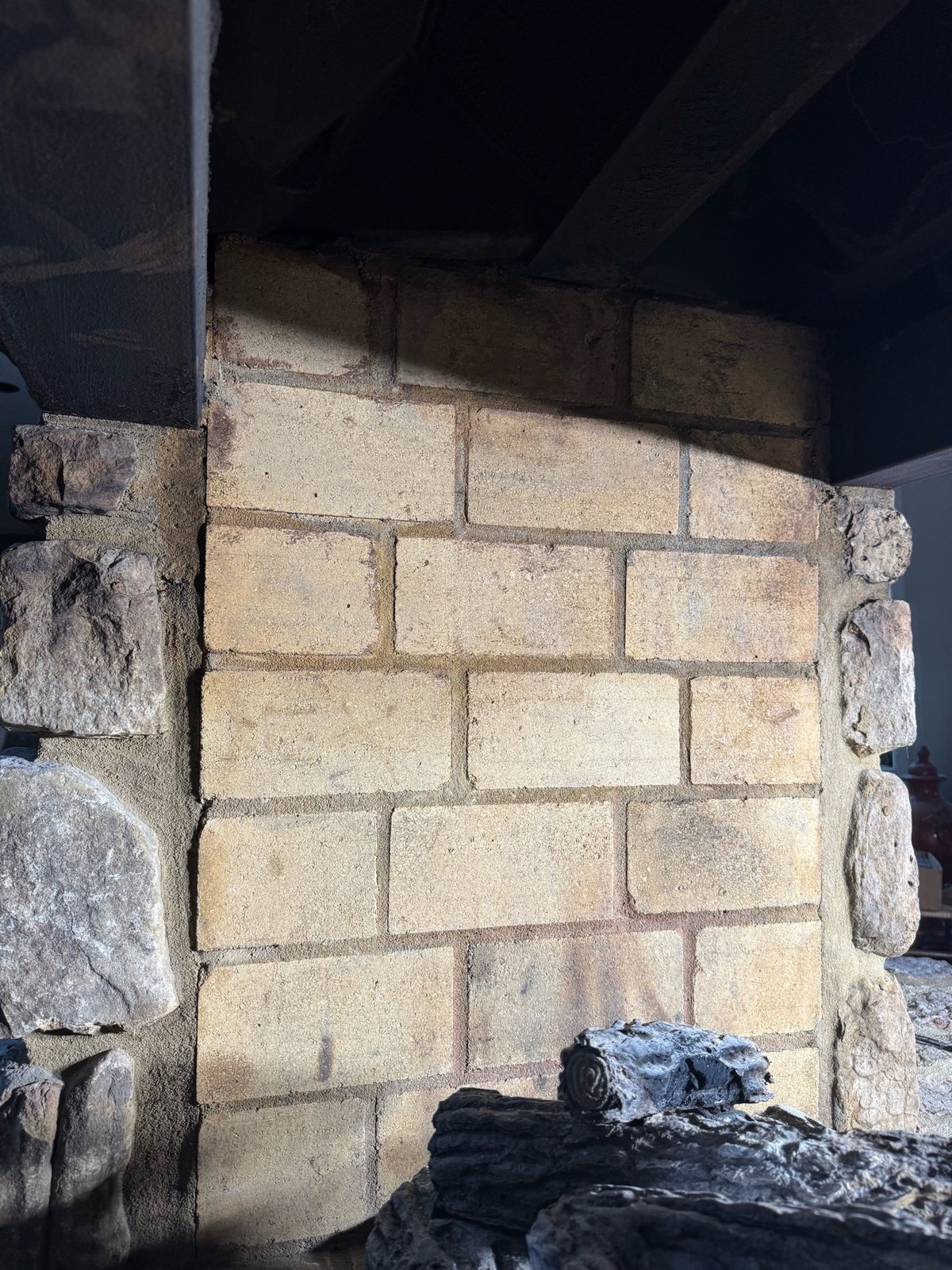 Fireplace firebrick after targeted soot removal, showing the lighter brick and mortar joints